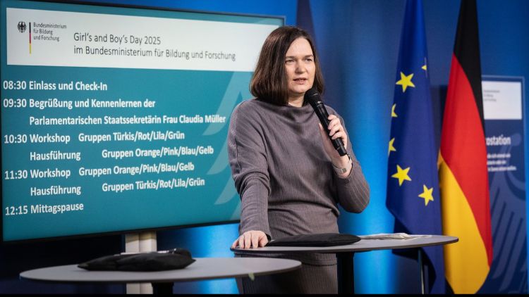 Parlamentarische Staatssekretärin Claudia Müller mit Mikrofon vor Bildschirm mit dem Tagesordnungsprogramm